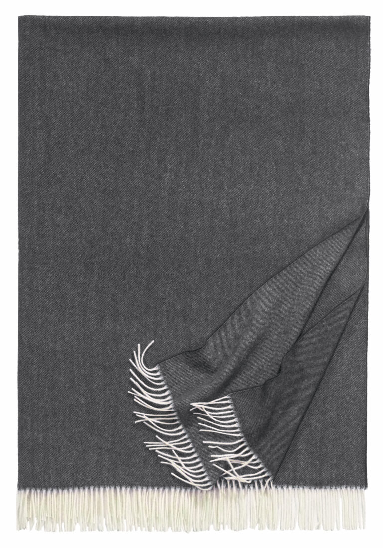 Grau-weißer Wollschal mit Fransen an den Enden, teilweise gefaltet.