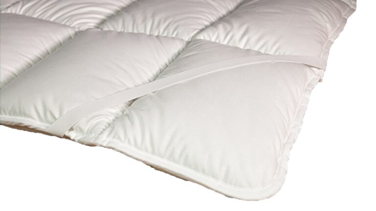 Nahaufnahme einer weißen, gesteppten Matratzenauflage mit elastischen Bändern an den Ecken.