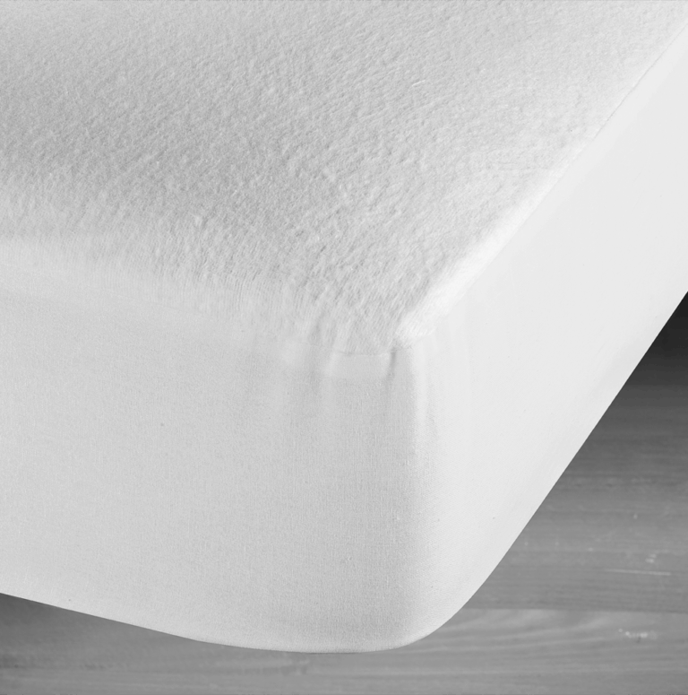 Nahaufnahme einer weißen Matratze mit einem flauschigen Spannbetttuch, das über die Ecke gespannt ist, auf einem Holzboden.