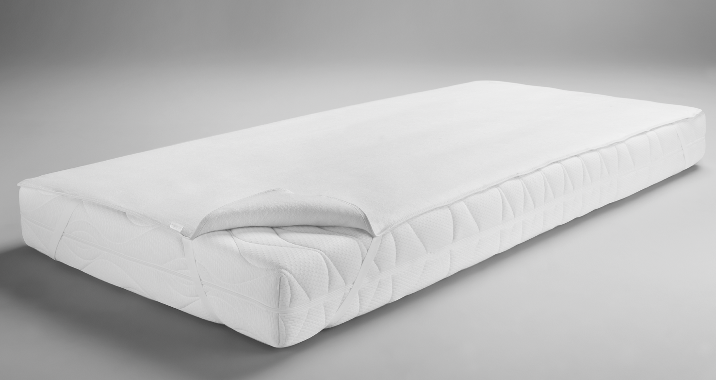 Ein weißer Matratzenschoner liegt auf einer Matratze, wobei eine Ecke des Schoners umgeschlagen ist.